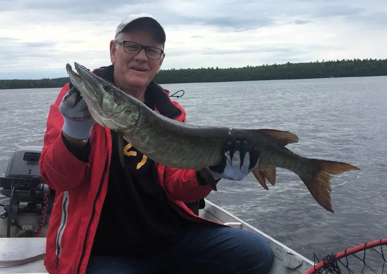 Pigeon Lake Resort Cottage Guests.&nbsp; Adult and children wearing life jackets holding a large fish on a boat on a lake.