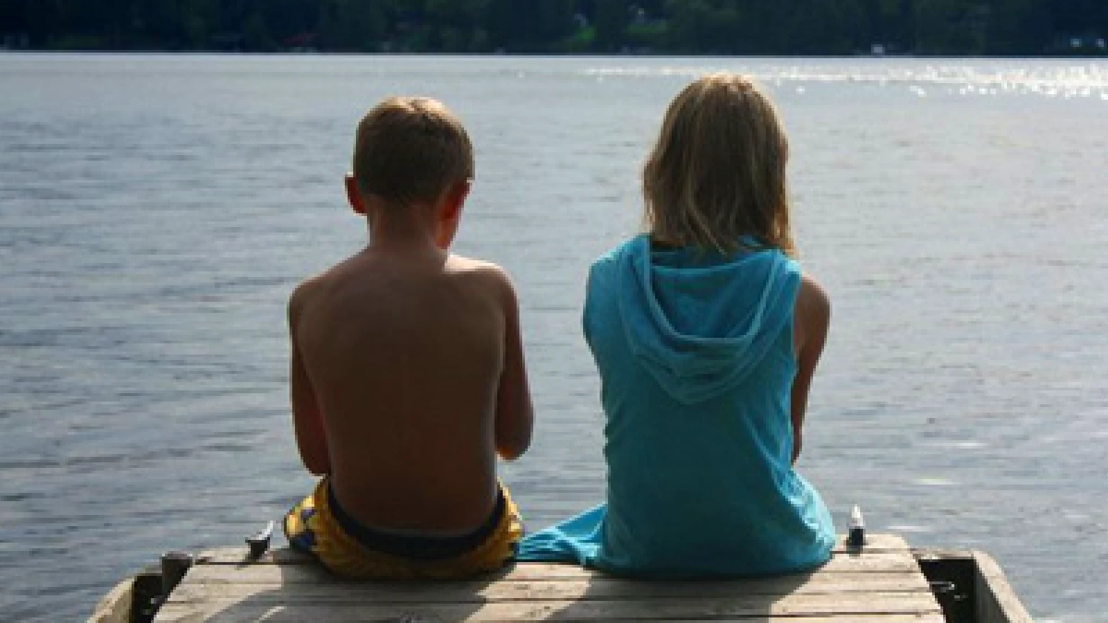 Children sitting on dock overlooking Pigeon Lake at cottage resort in Kawartha Lakes Ontario