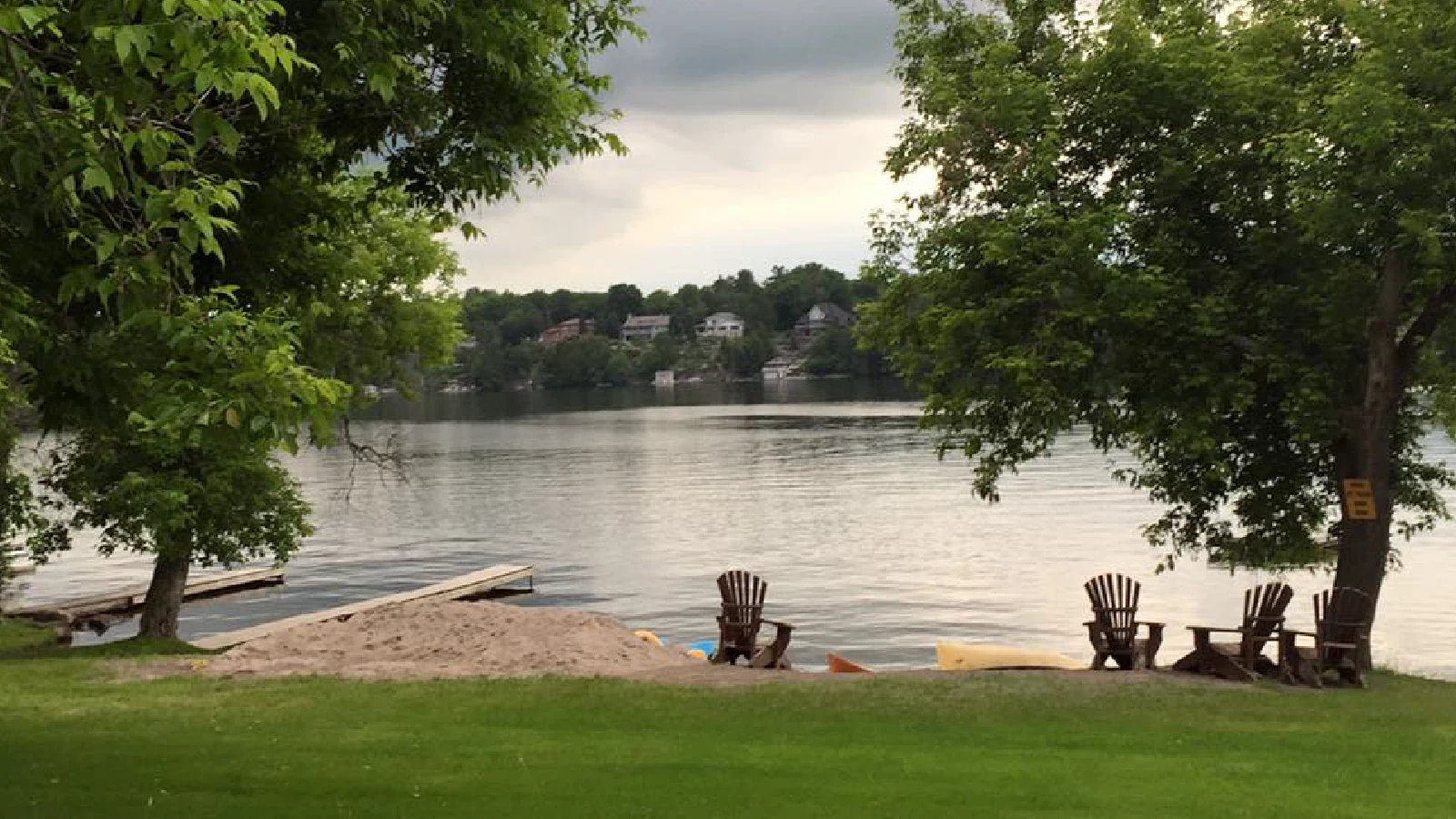 Sandy beach and swimming area with Adirondack chairs on Pigeon Lake at cottage resort in Kawartha Lakes Ontario